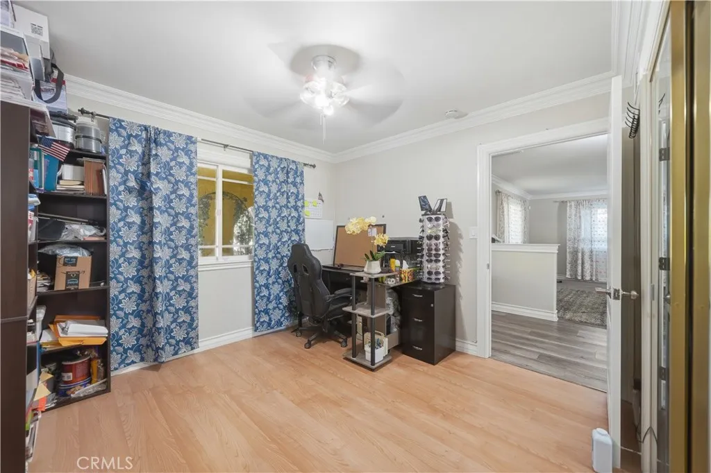 Downstairs with laminate floors near the front entry of the home, with mirrored closet doors and ceiling fan.