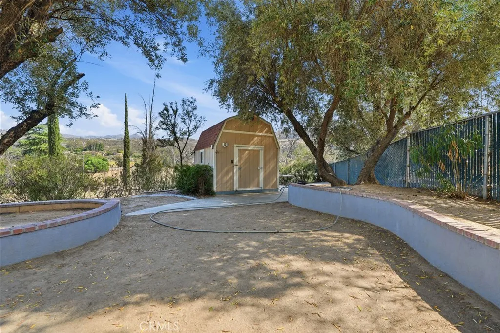 Large shed sits at the back of the property with concrete walkways around it.