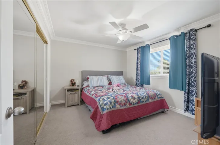 Second floor guest bedroom with ceiling fan and mirrored bipass closet doors