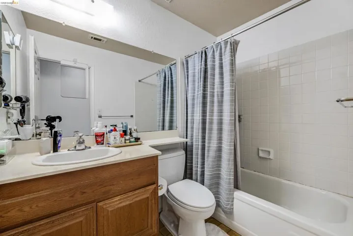 Bathroom featuring a single vanity with wood-finish cabinetry, a built-in sink, and a large mirror