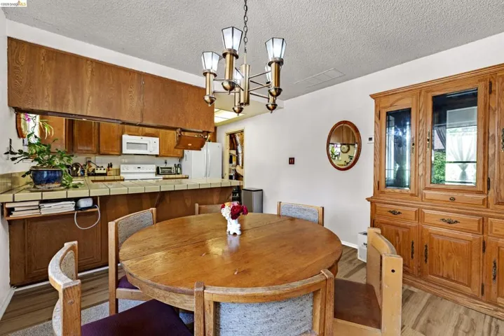 Dining area with a brass chandelier, wood-finish flooring, and built-in wood cabinetry