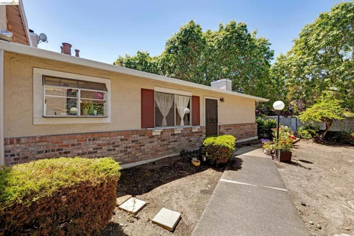 Exterior facade featuring stucco siding, brick detailing, and red-shuttered windows