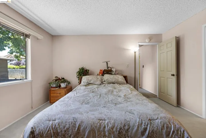 Bedroom featuring neutral-toned walls, carpeted flooring, a window with blinds, and a paneled interior door