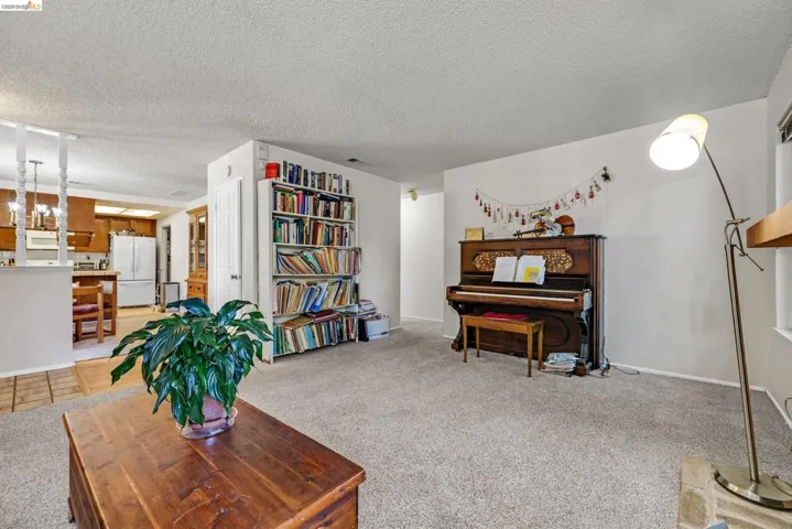 Carpeted living area with a built-in bookcase, white walls, and a textured ceiling