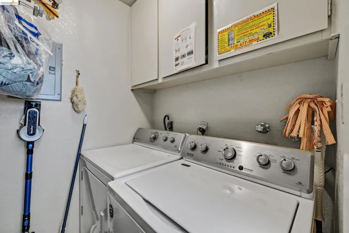 Dedicated laundry area featuring white wall cabinetry, a built-in shelf, and appliance hookups