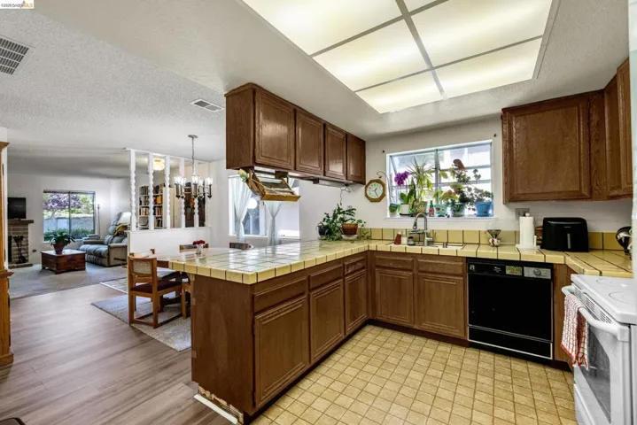 Kitchen featuring wood cabinetry, tile countertops, and a built-in dishwasher