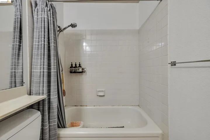 Shower-over-tub design featuring white subway tile surround, a chrome shower head, and a wall-mounted towel bar