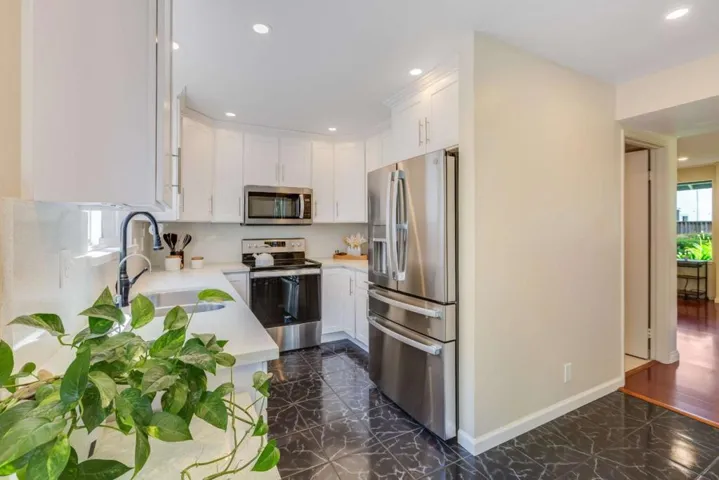 Bright kitchen with stainless steel appliances, new cabinetry, & quartz countertops