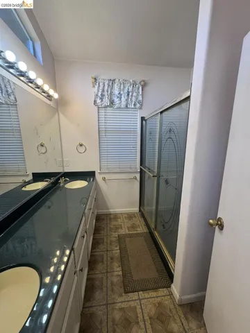 Dual vanity featuring integrated sinks, a dark countertop, and white cabinetry