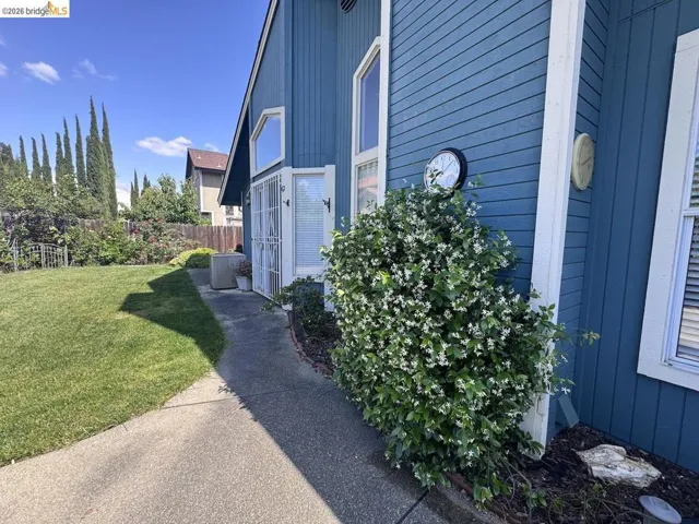 Expansive side yard featuring a lush lawn, concrete pathway, and a privacy fence