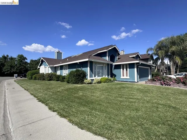 Blue exterior siding with white trim accents and a brown shingle roof