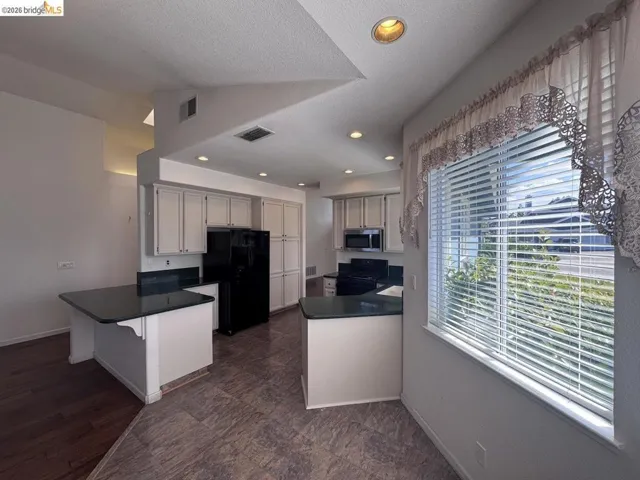 Bright kitchen with white cabinetry and dark countertops