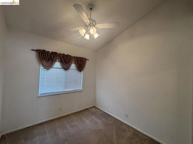 Carpeted room featuring a ceiling fan with integrated lighting, a window with horizontal blinds, and white baseboards