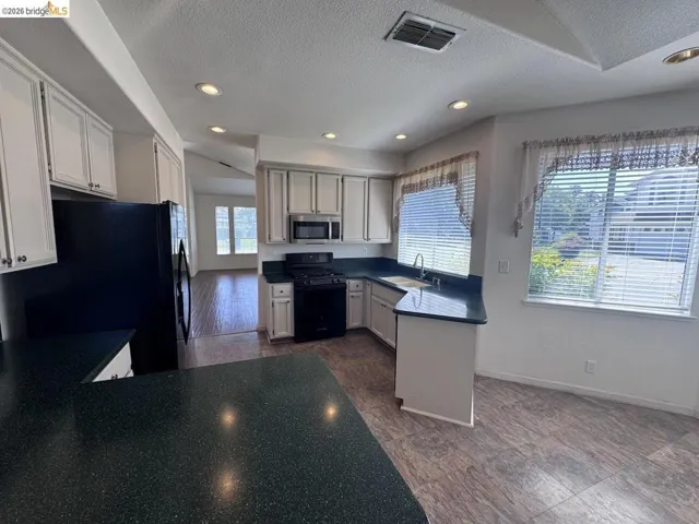 Kitchen featuring white cabinetry, dark countertops, built-in appliances, recessed lighting, and wood-finish flooring
