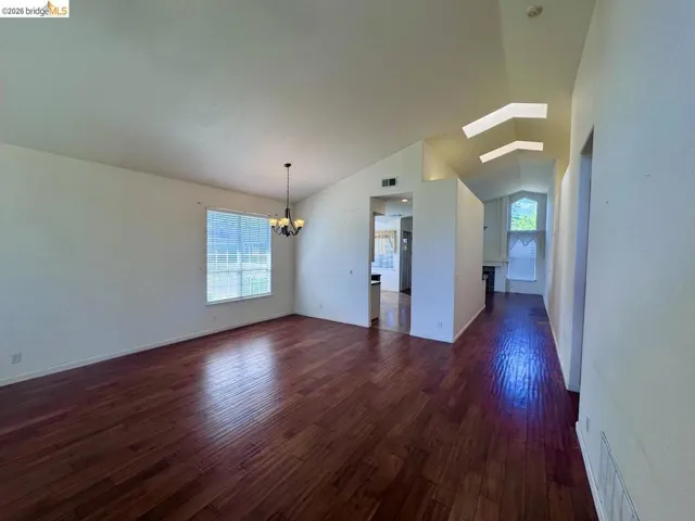 Spacious interior with rich wood-finish flooring, vaulted ceilings, and a contemporary chandelier