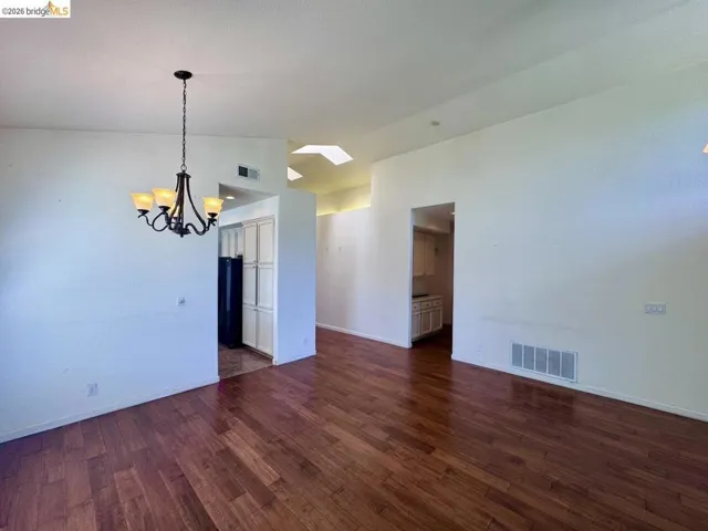 Spacious interior featuring wood-finish flooring, a vaulted ceiling, and a traditional chandelier