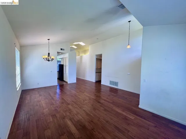 Spacious interior featuring wood-finish flooring, vaulted ceilings, and a window with blinds