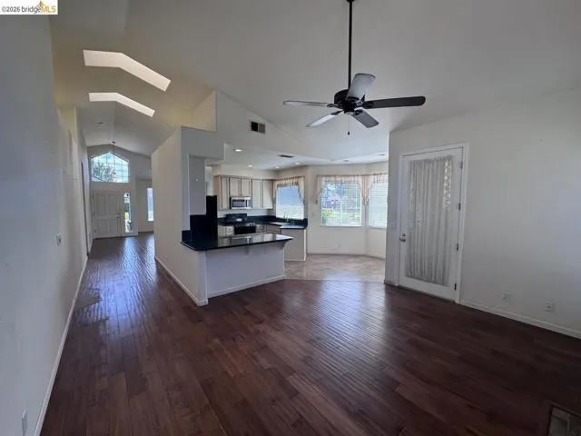 Expansive open-concept living area featuring wood-finish flooring, vaulted ceilings, and skylights