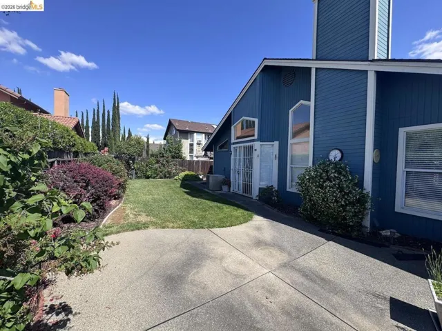 Blue exterior siding with white trim, arched windows, and a paved pathway leading to a grass lawn