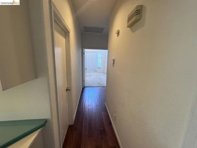 Hallway featuring wood-finish flooring, white walls, and a recessed ceiling light