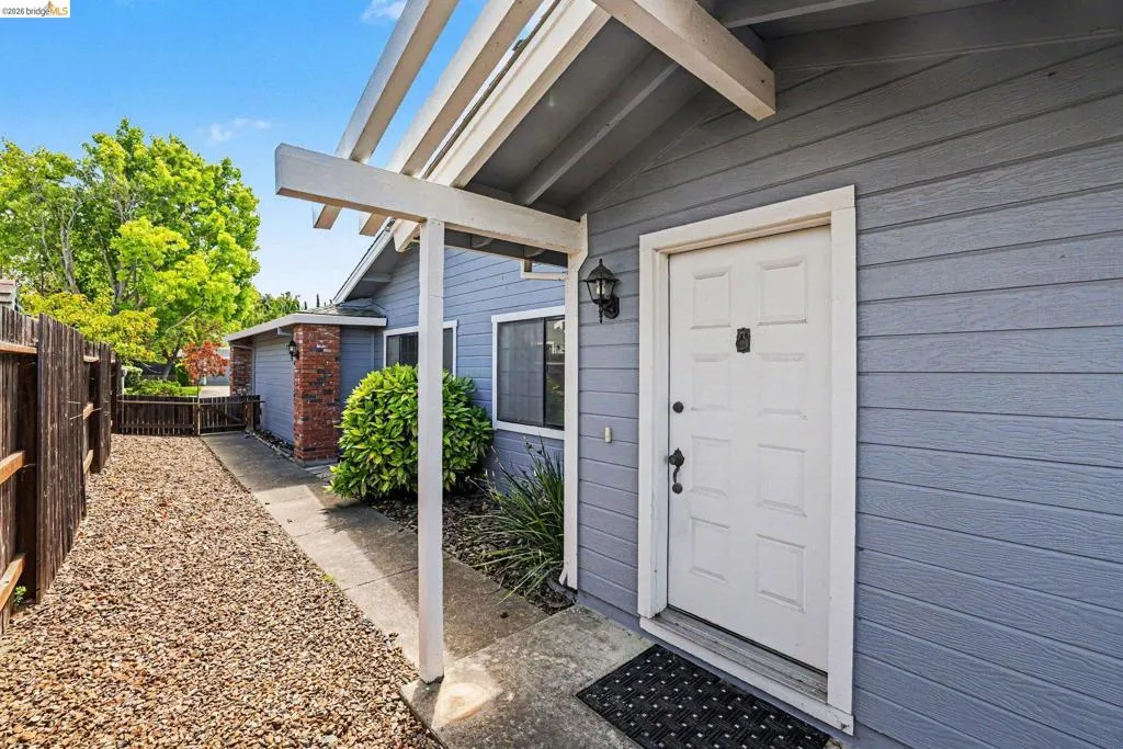 Entryway featuring a white paneled door with black hardware, flanked by gray horizontal siding