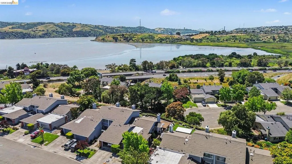 Waterside community with residential properties, mature landscaping, and a distant bridge