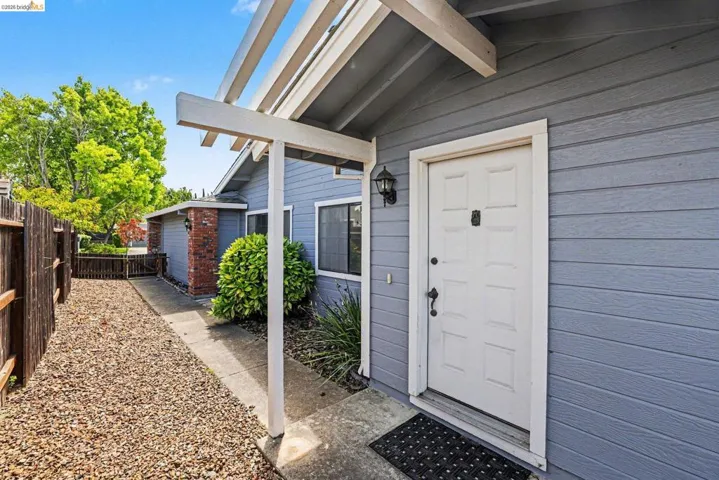 Entryway featuring a white paneled door with black hardware, flanked by gray horizontal siding