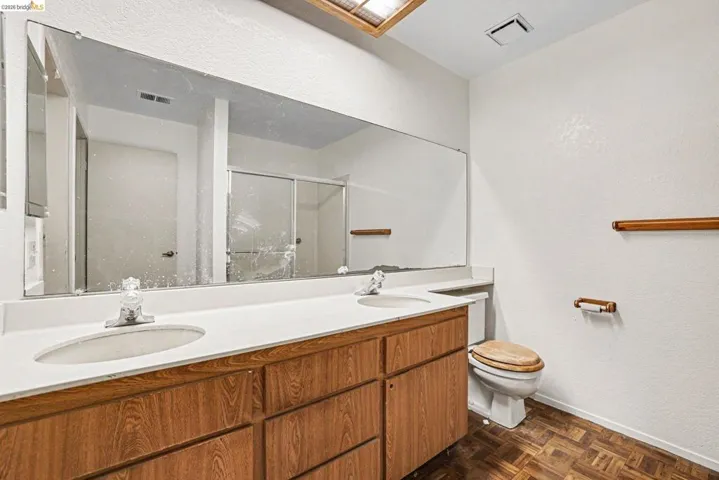 Bathroom featuring a wood-finish double vanity with white countertops and two integrated sinks