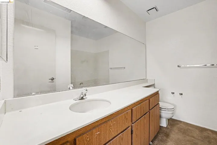 Bathroom featuring an extended vanity with wood-finish cabinetry and a white solid surface countertop
