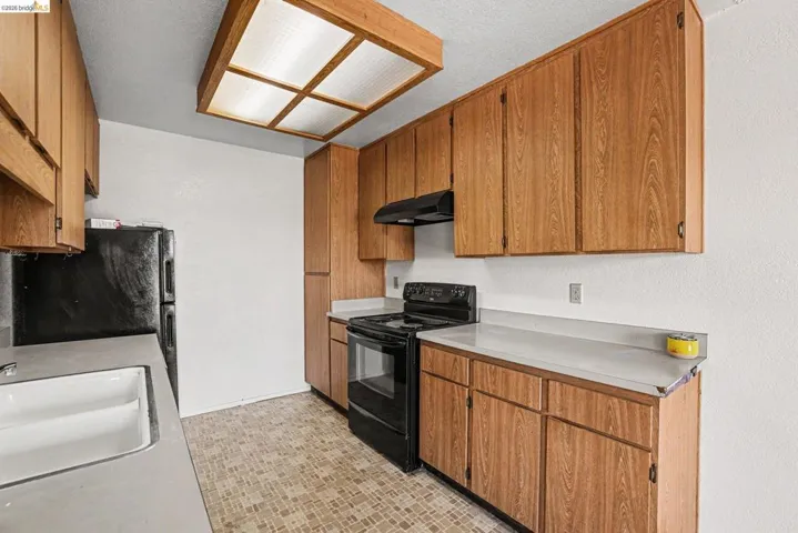 Kitchen featuring wood-finish cabinetry, light countertops, and a white double-basin sink