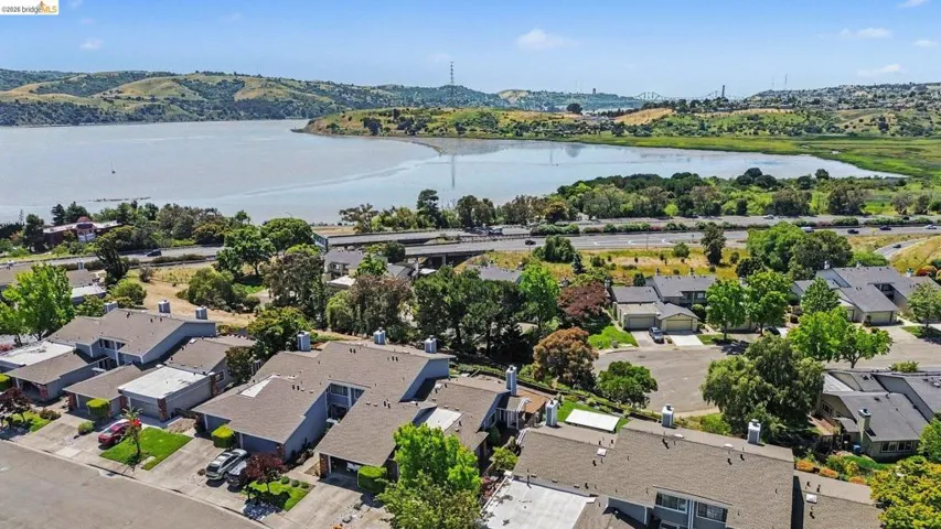 Waterside community with residential properties, mature landscaping, and a distant bridge