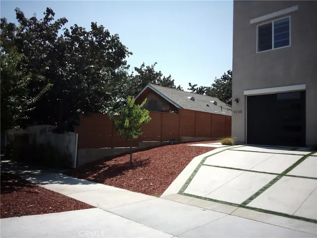 Exterior side perspective with high fencing and adjacent property.