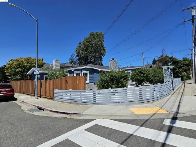 Corner property featuring a blue exterior, stone chimney, and a combination of wood and slatted composite fencing