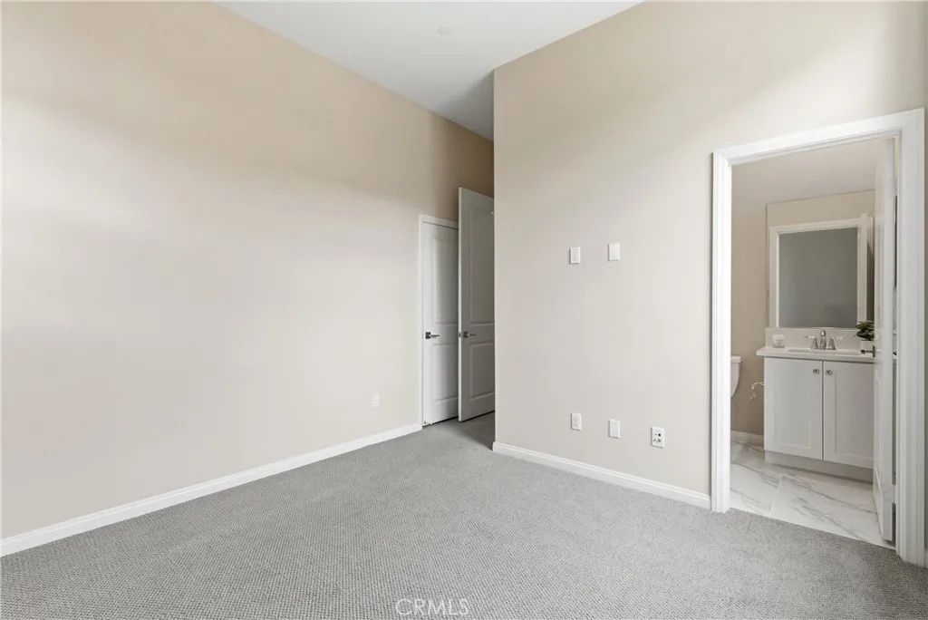 Spacious secondary bedroom with direct access to an en-suite bathroom, soft neutral finishes, and ample wall space for furnishings.