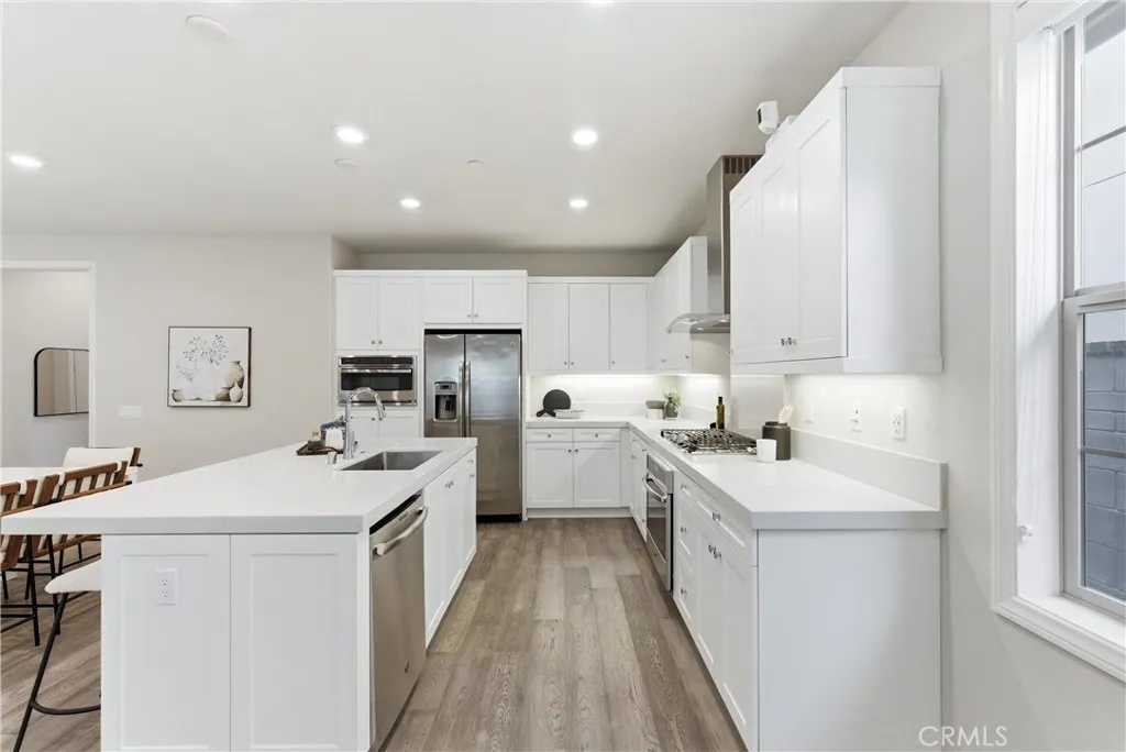 Bright and modern kitchen with expansive quartz island, stainless steel sink, gas cooktop, under-cabinet lighting, and open layout ideal for entertaining.