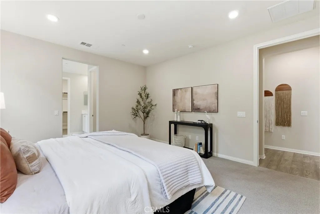 Expansive primary suite with neutral designer finishes, oversized layout, plush carpeting, and adjacent walk-in closet and en-suite bath.