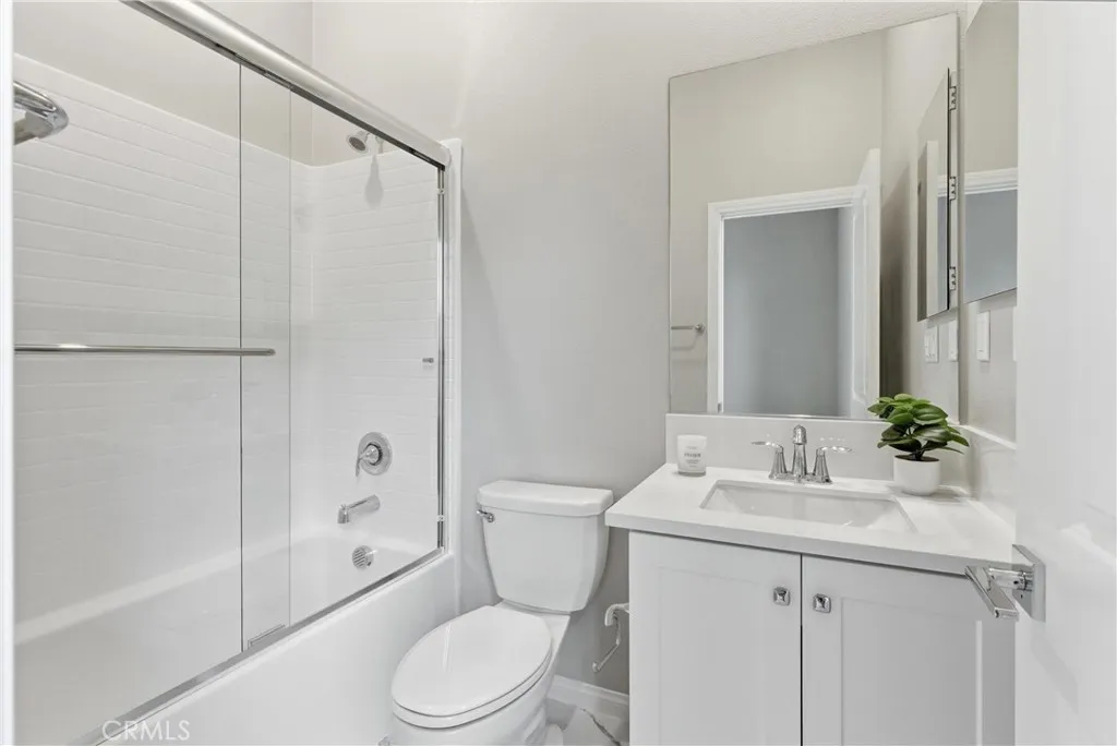 Private en-suite bathroom featuring a quartz vanity, upgraded fixtures, shower and tub combination with glass enclosure, and modern finishes.