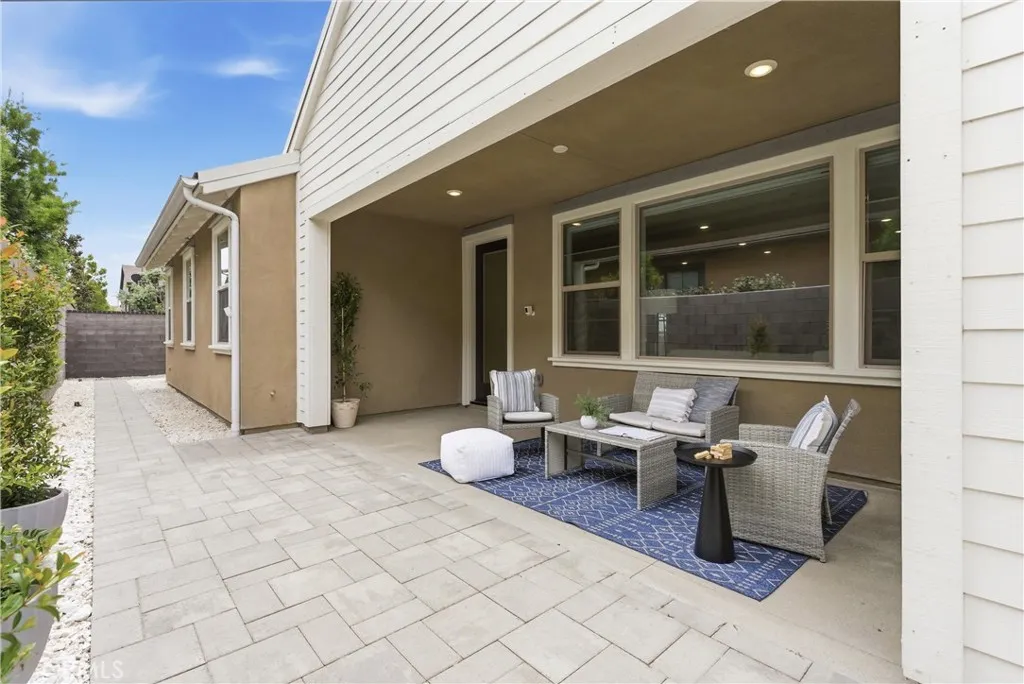 Extended outdoor living space featuring covered patio seating area, large paver patio, and seamless access to the interior living room.