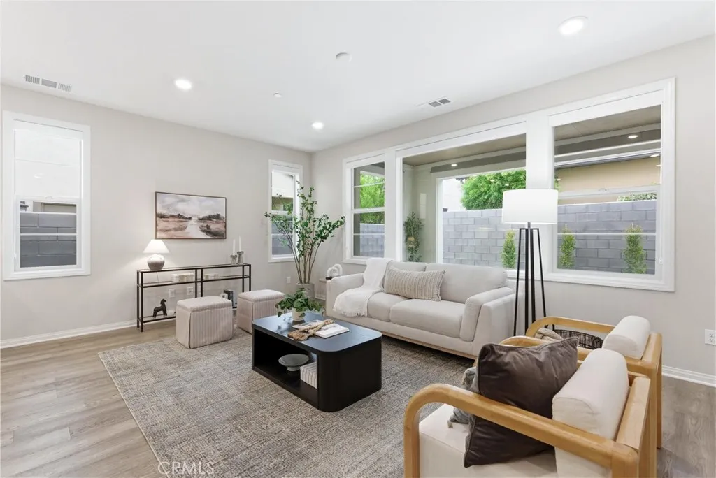 Spacious living room with oversized windows, abundant natural light, recessed lighting, and open floor plan adjacent to the kitchen and dining area.