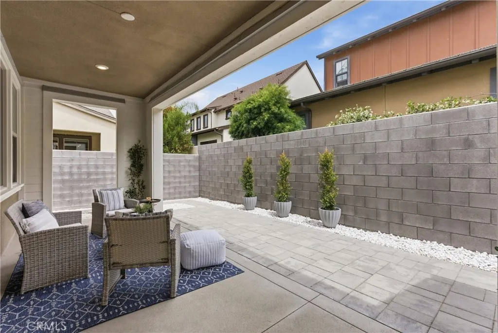 Private covered patio with recessed lighting, spacious paver hardscape, and low-maintenance landscaping ideal for outdoor dining and entertaining.