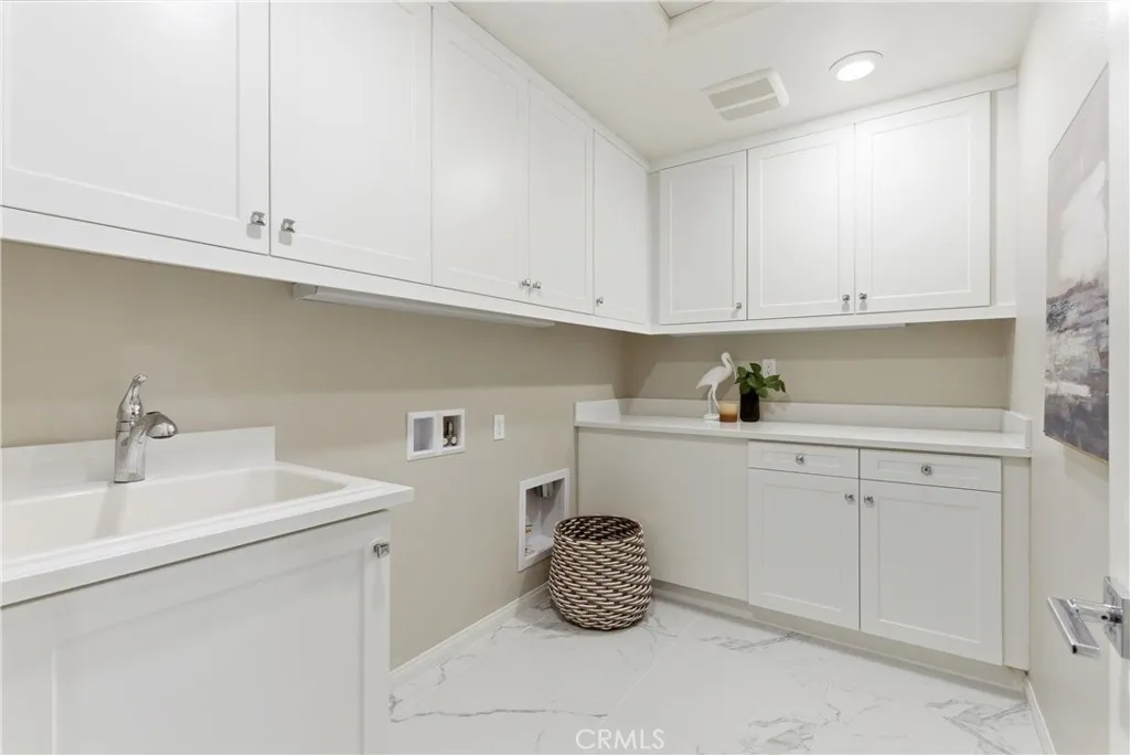 Dedicated laundry room with built-in cabinetry, utility sink, generous counter space, and ample storage for organization and convenience.