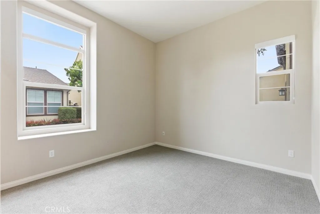 Secondary bedroom with large windows, plush carpet flooring, natural light, and flexible use as a guest room or home office.