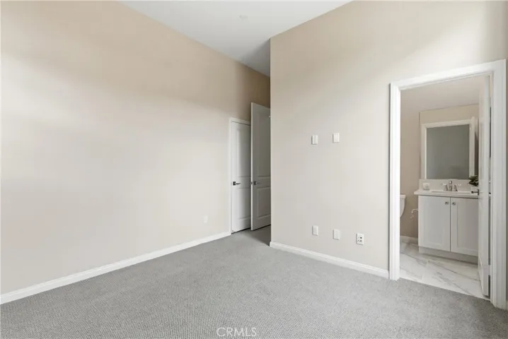 Spacious secondary bedroom with direct access to an en-suite bathroom, soft neutral finishes, and ample wall space for furnishings.