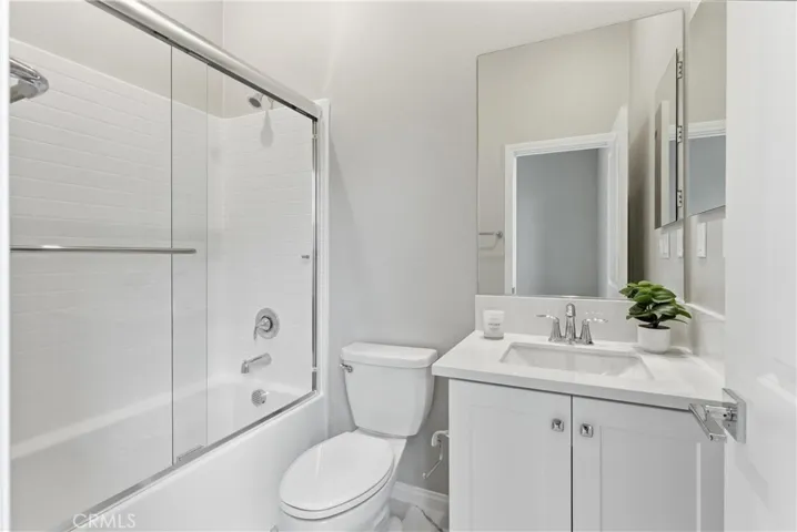Private en-suite bathroom featuring a quartz vanity, upgraded fixtures, shower and tub combination with glass enclosure, and modern finishes.