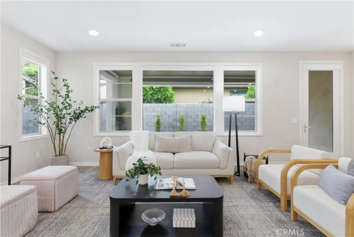Bright great room featuring expansive windows, neutral designer finishes, luxury vinyl plank flooring, and access to the private outdoor patio.