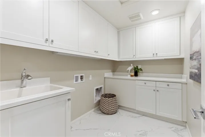 Dedicated laundry room with built-in cabinetry, utility sink, generous counter space, and ample storage for organization and convenience.