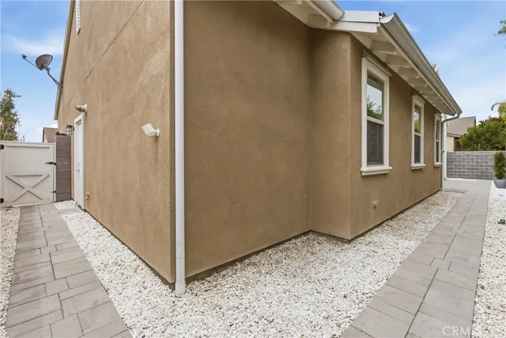 Side yard with paved walkways, decorative rock landscaping, gated access, and low-maintenance exterior design.