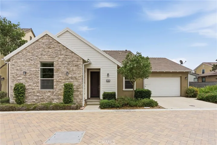 Single-story detached home with modern farmhouse-inspired exterior, stone accent façade, attached two-car garage, and professionally maintained landscaping in Rancho Mission Viejo.