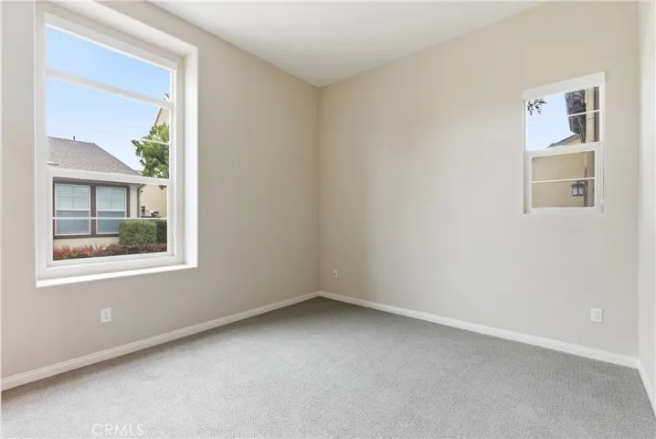 Secondary bedroom with large windows, plush carpet flooring, natural light, and flexible use as a guest room or home office.