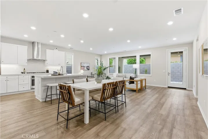 Open-concept great room with expansive living and dining areas, recessed lighting, luxury vinyl plank flooring, and seamless indoor-outdoor flow.